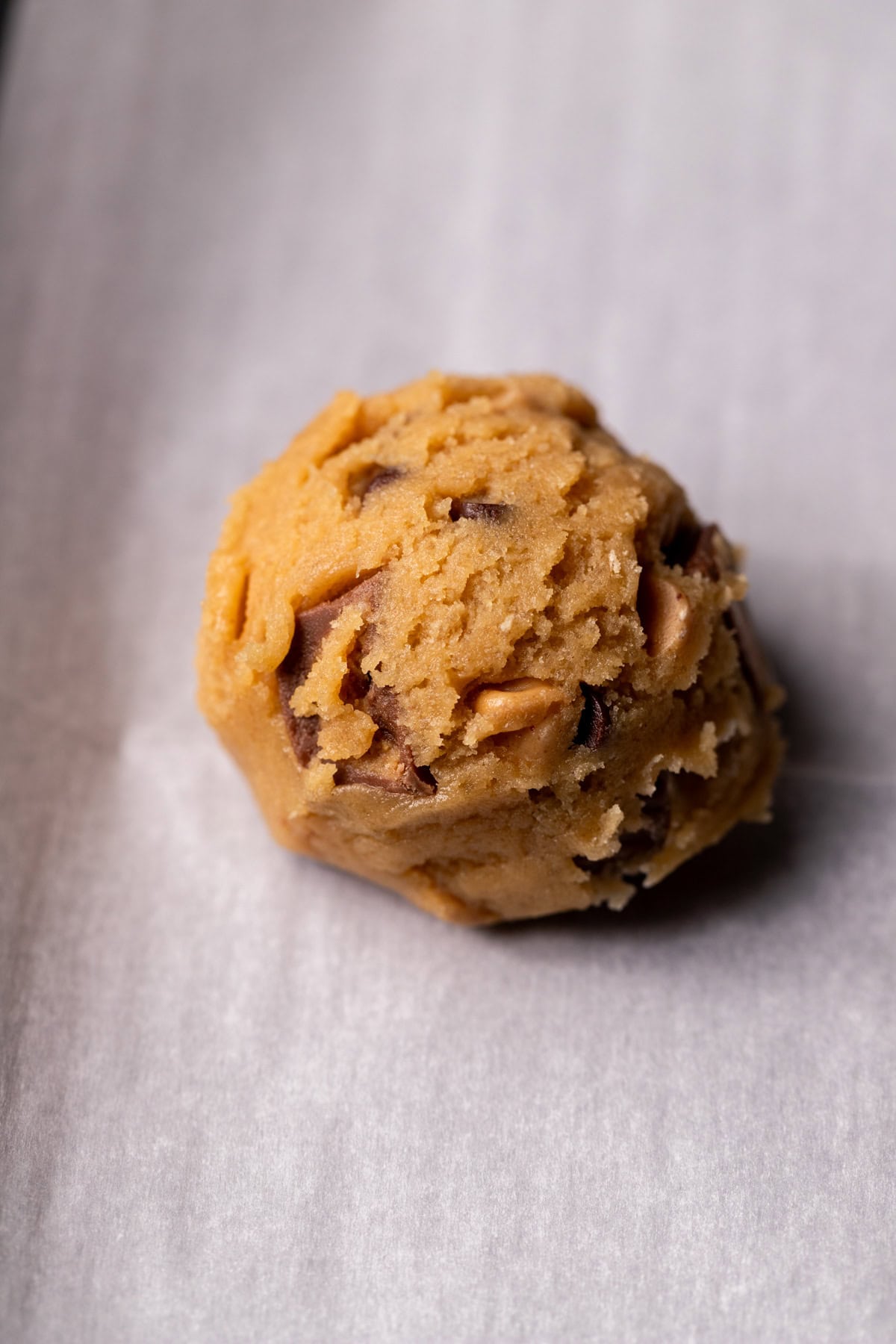 Cookie dough ball on parchment paper.
