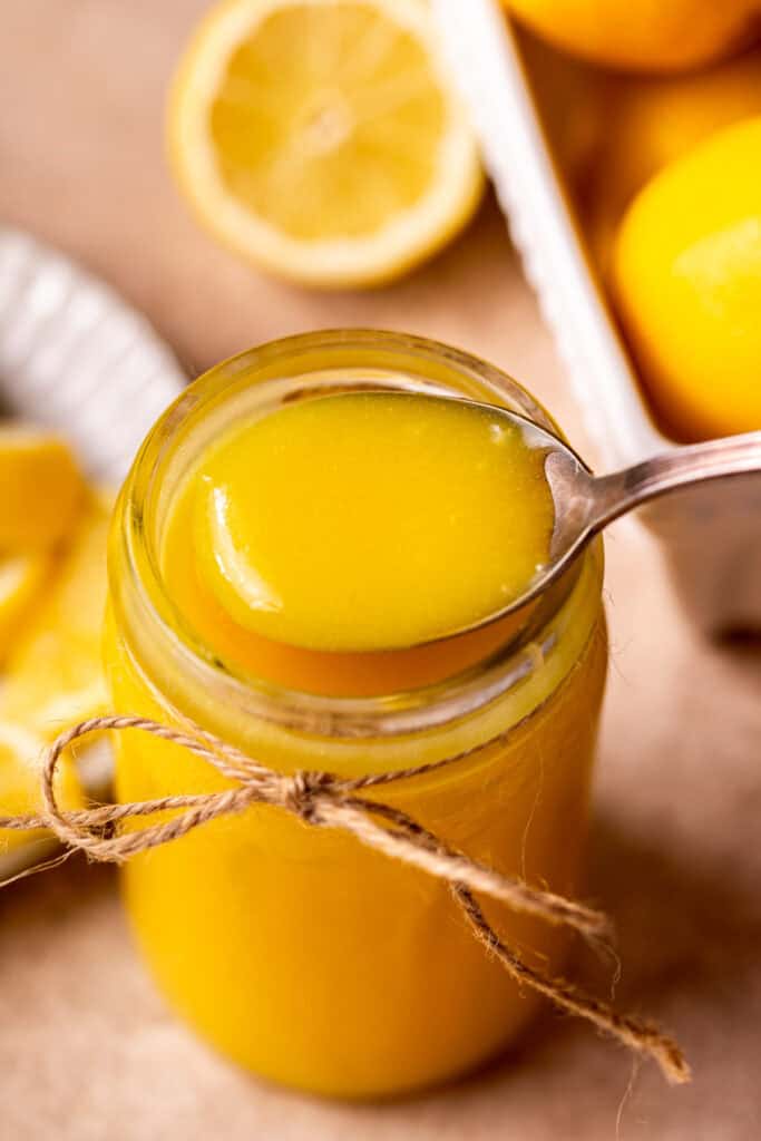 Taking a spoon of lemon curd out of the jar.