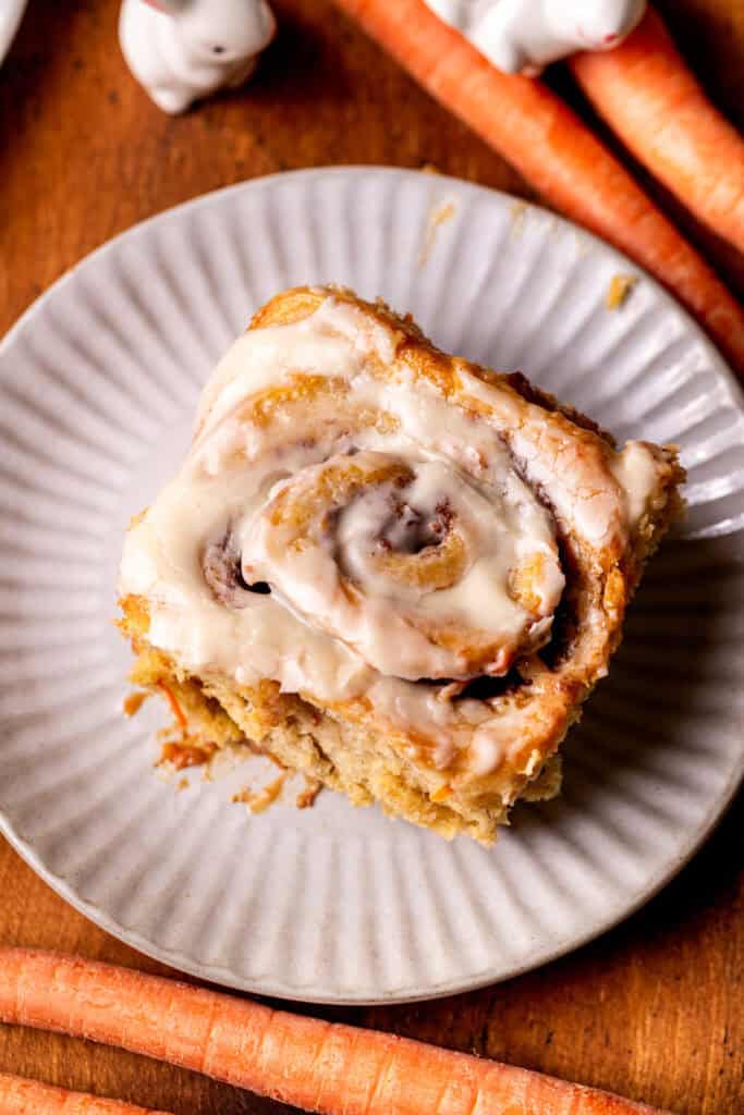 Top view of one carrot cake cinnamon roll on a plate.