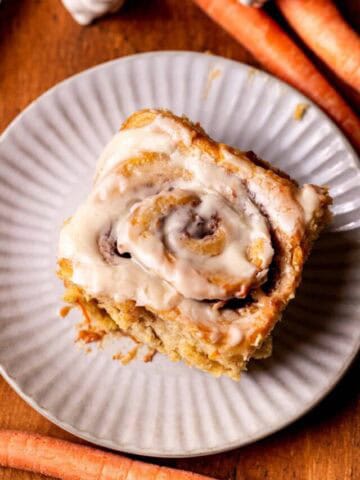 Top view of one carrot cake cinnamon roll on a plate.