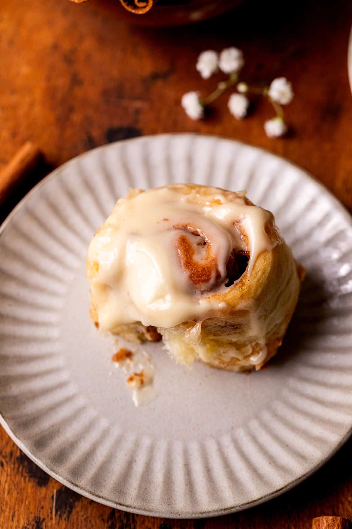 One mini cinnamon roll on a plate.