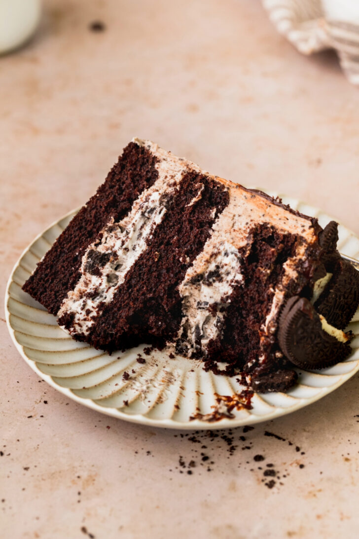 Oreo cake slice on a plate with a bite missing.