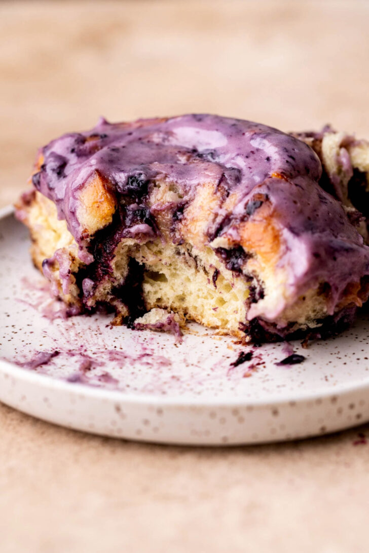 Side view of a blueberry cinnamon roll with a bite missing.
