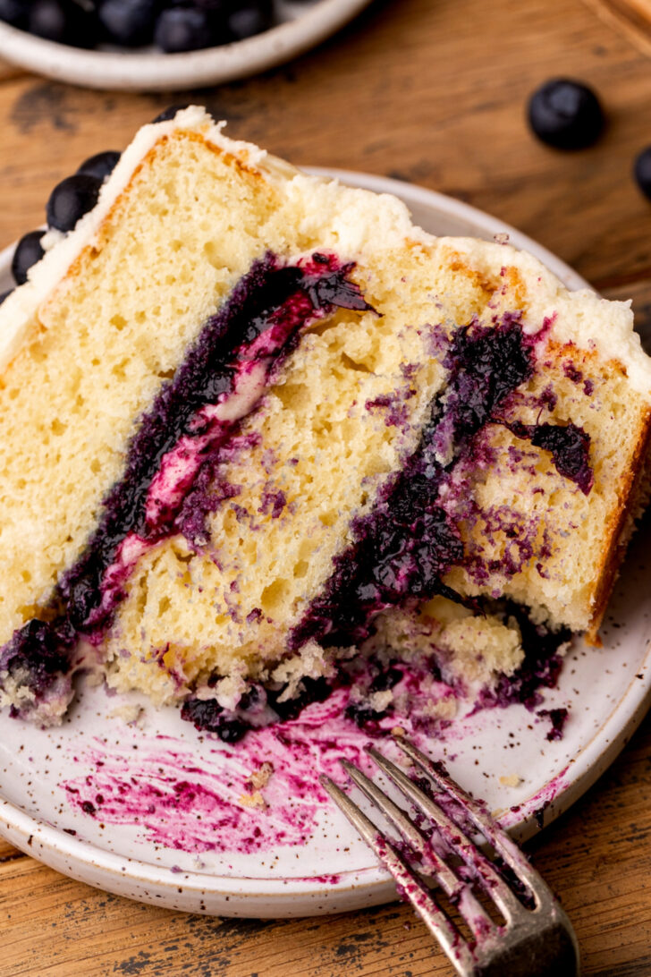 A bite missing from blueberry jam cake on a plate.