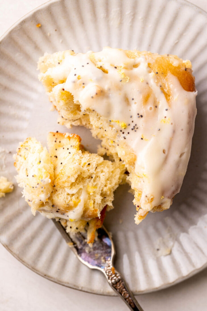 Bite missing from lemon roll on a plate.