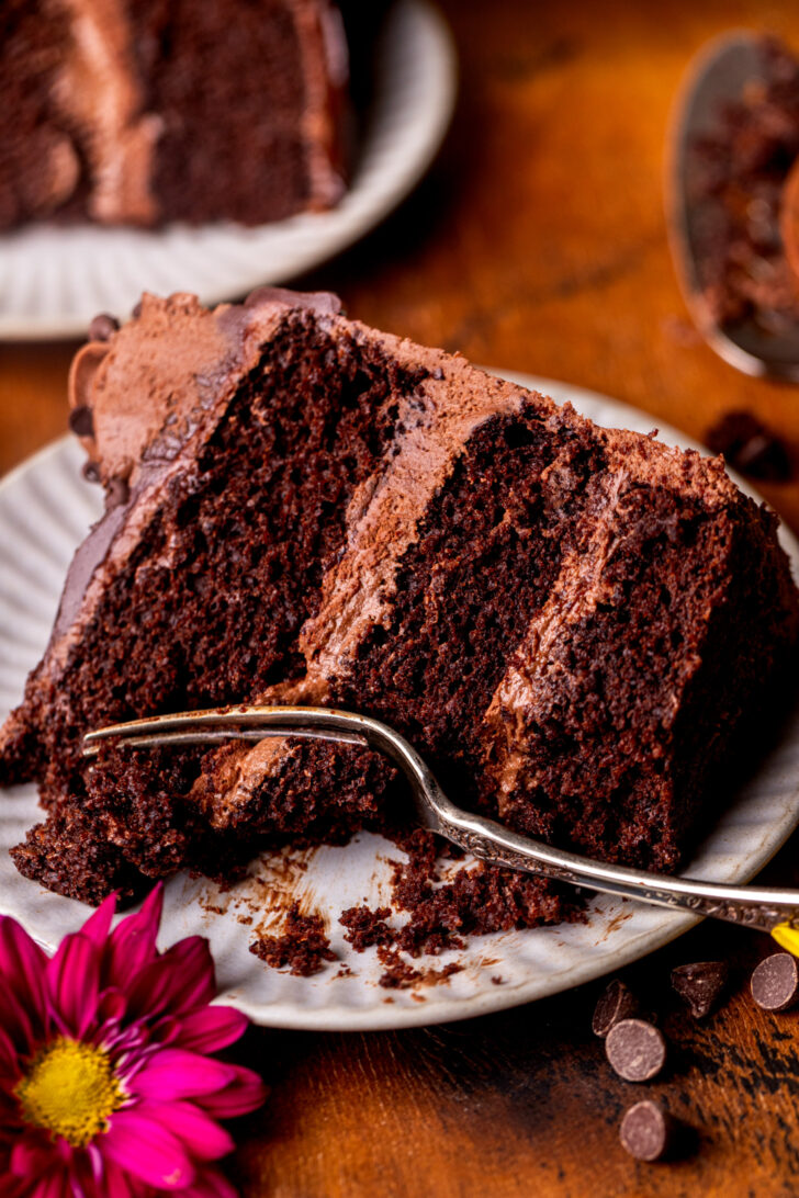Fork inserted into a slice of triple chocolate cake.