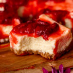 One strawberry cheesecake bars with a bite missing.
