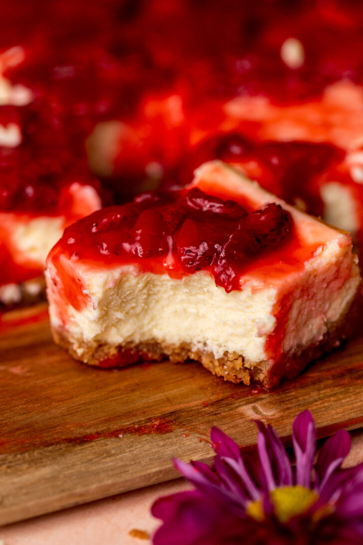 One strawberry cheesecake bars with a bite missing.