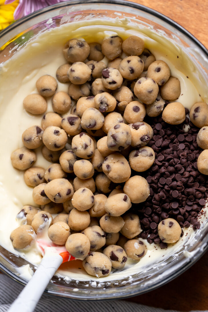 Cookie dough balls on top of cheesecake batter.