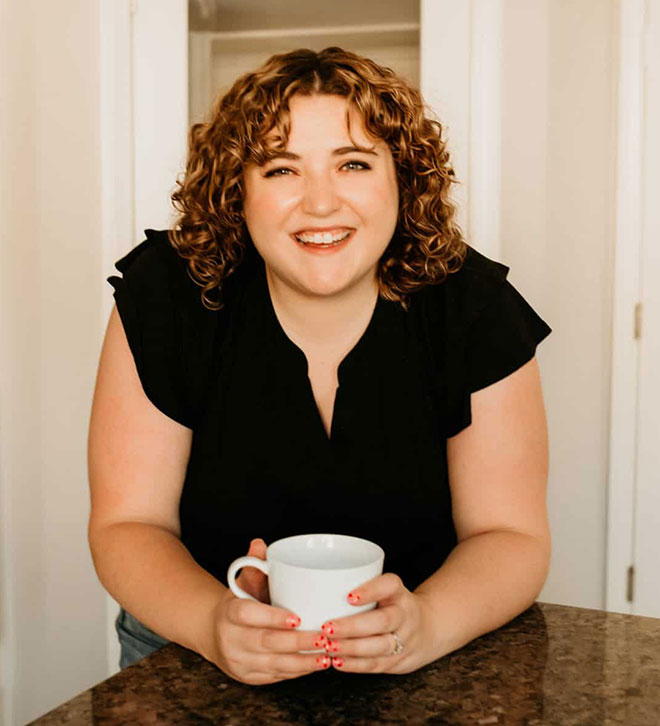 Stephanie headshot in black shirt with coffee cup.