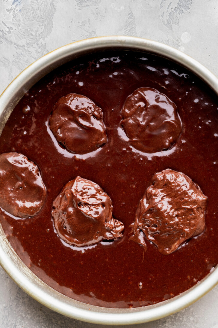 Brownie scoops on top of cake batter.