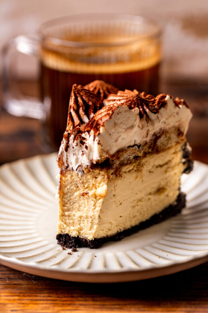 Bite missing from a slice of cheesecake on a plate.