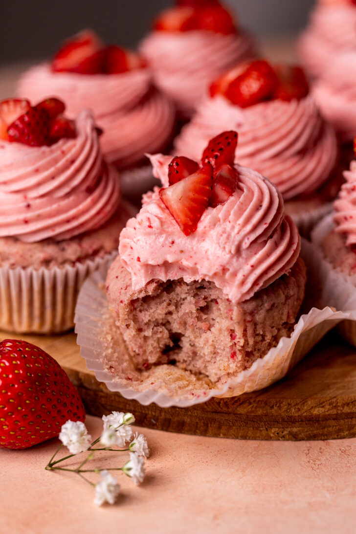 Bite missing from strawberry cupcakes.