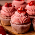 One strawberry cupcake on a wood board.