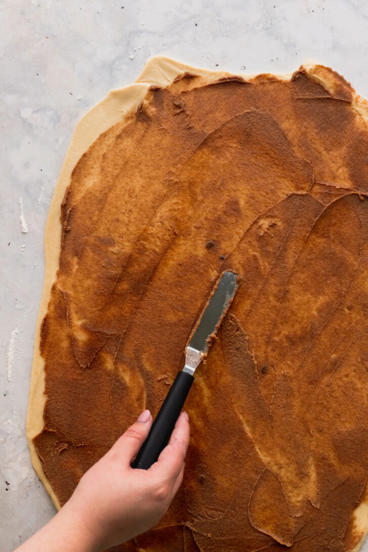 Spreading cinnamon filling on the dough.