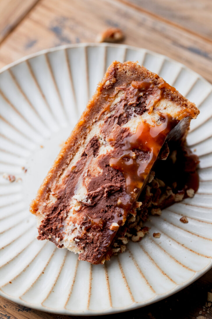 One slice of turtle cheesecake on a plate.
