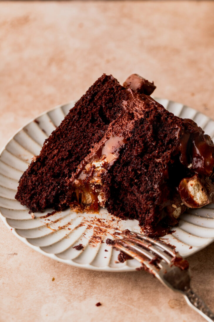 Bite missing from piece of cake on a plate.