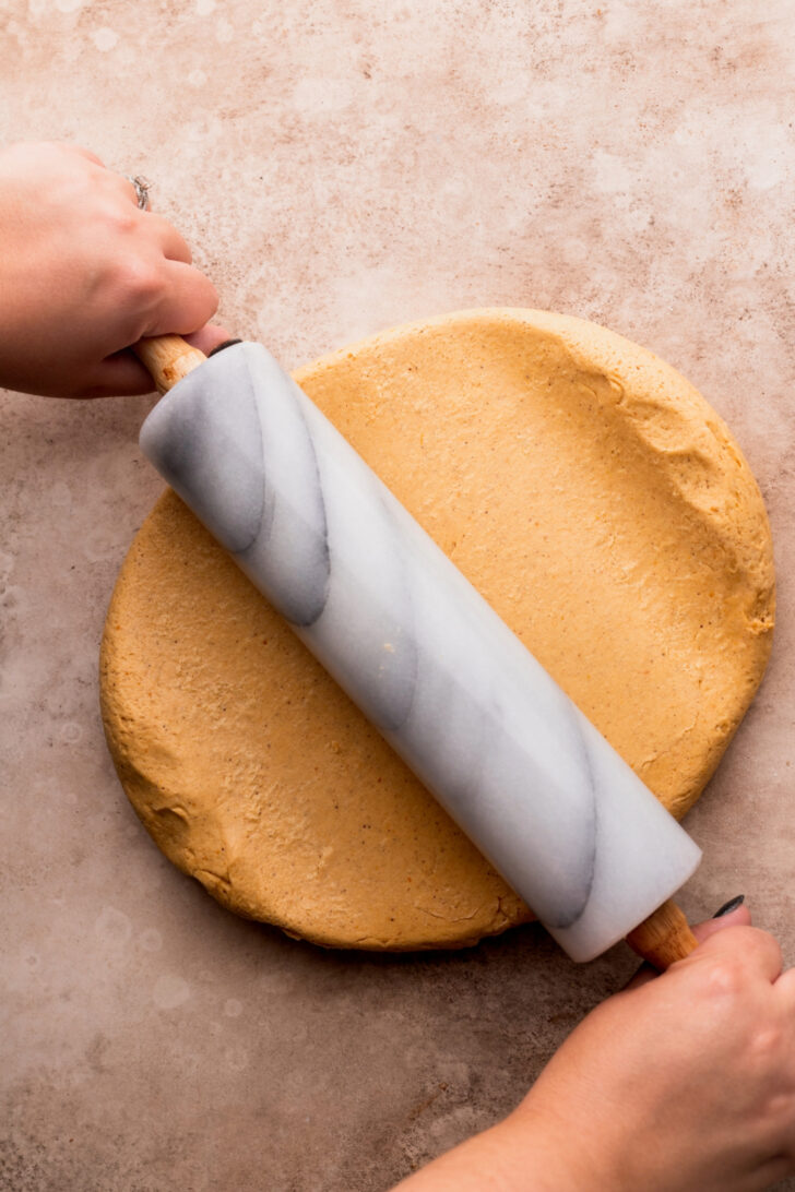 Using a rolling pin to roll out the rolls.