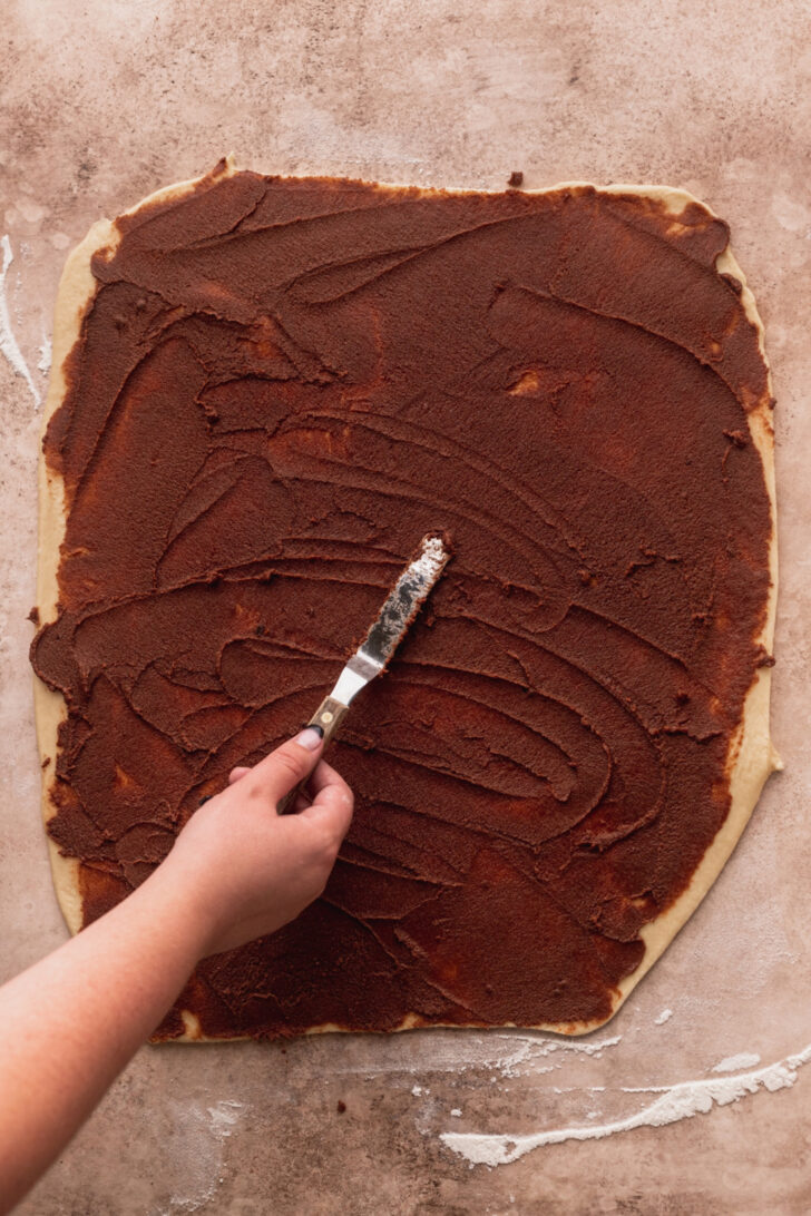 Spreading cinnamon filling over the dough.