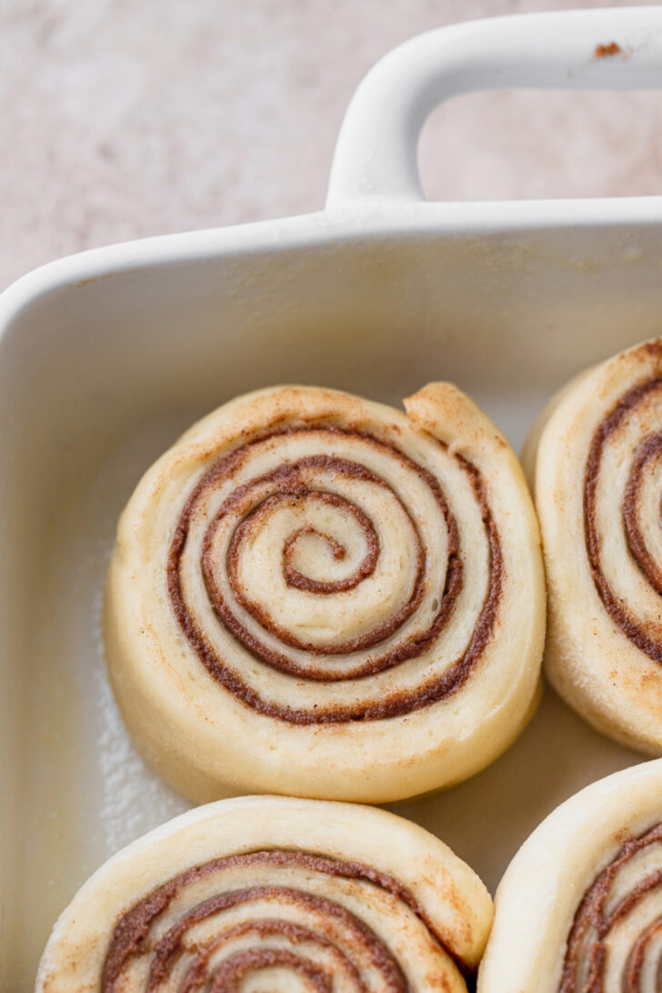 Raw cinnamon rolls in a pan.
