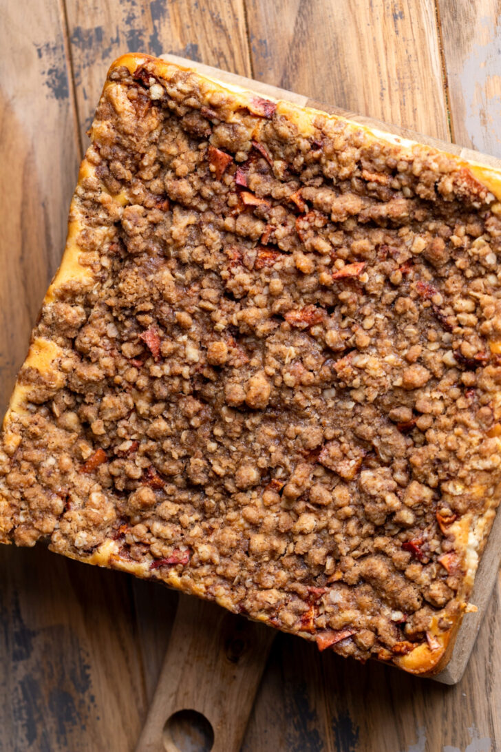 Baked cheesecake bars on a wood board.