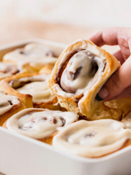 Pulling homemade cinnamon rolls out of the pan.