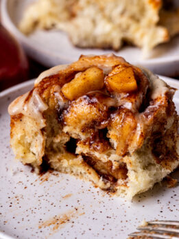 Bite missing from apple cinnamon rolls on a plate.