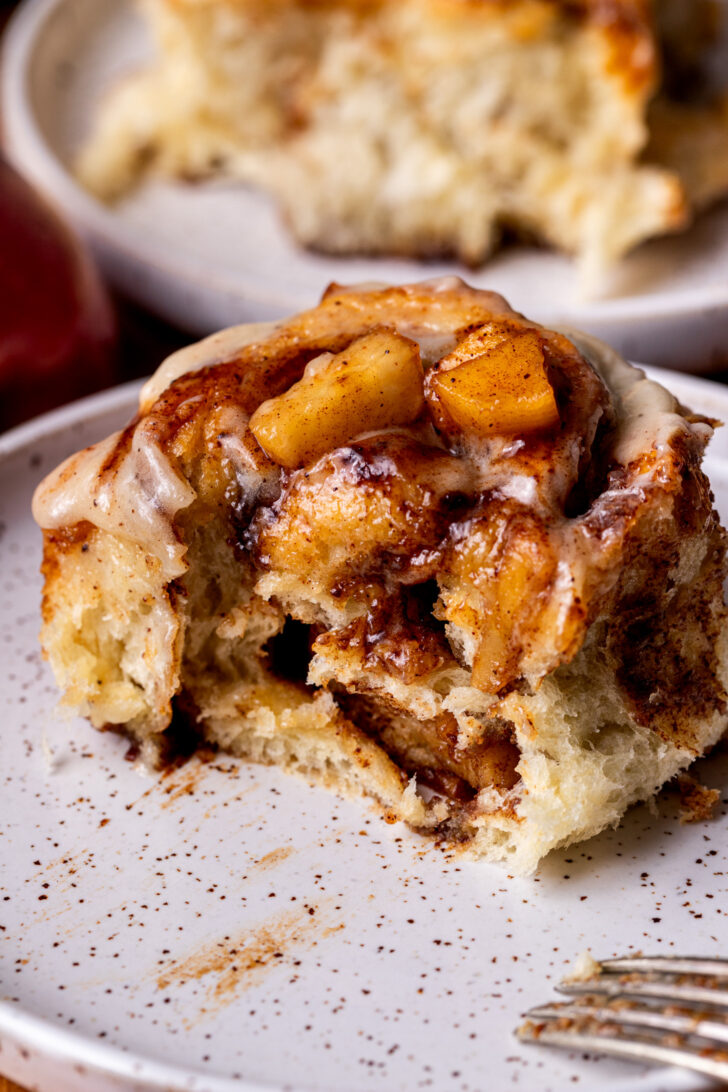 Bite missing from apple cinnamon rolls on a plate.