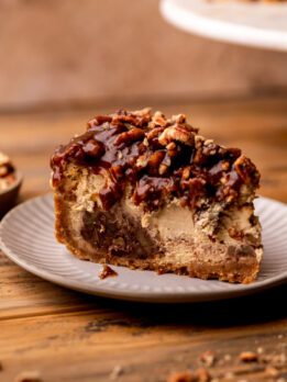 One slice of pecan pie cheesecake on a plate.