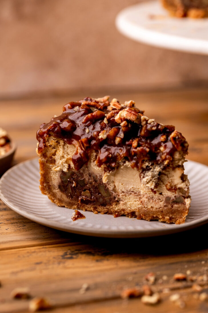 One slice of pecan pie cheesecake on a plate.