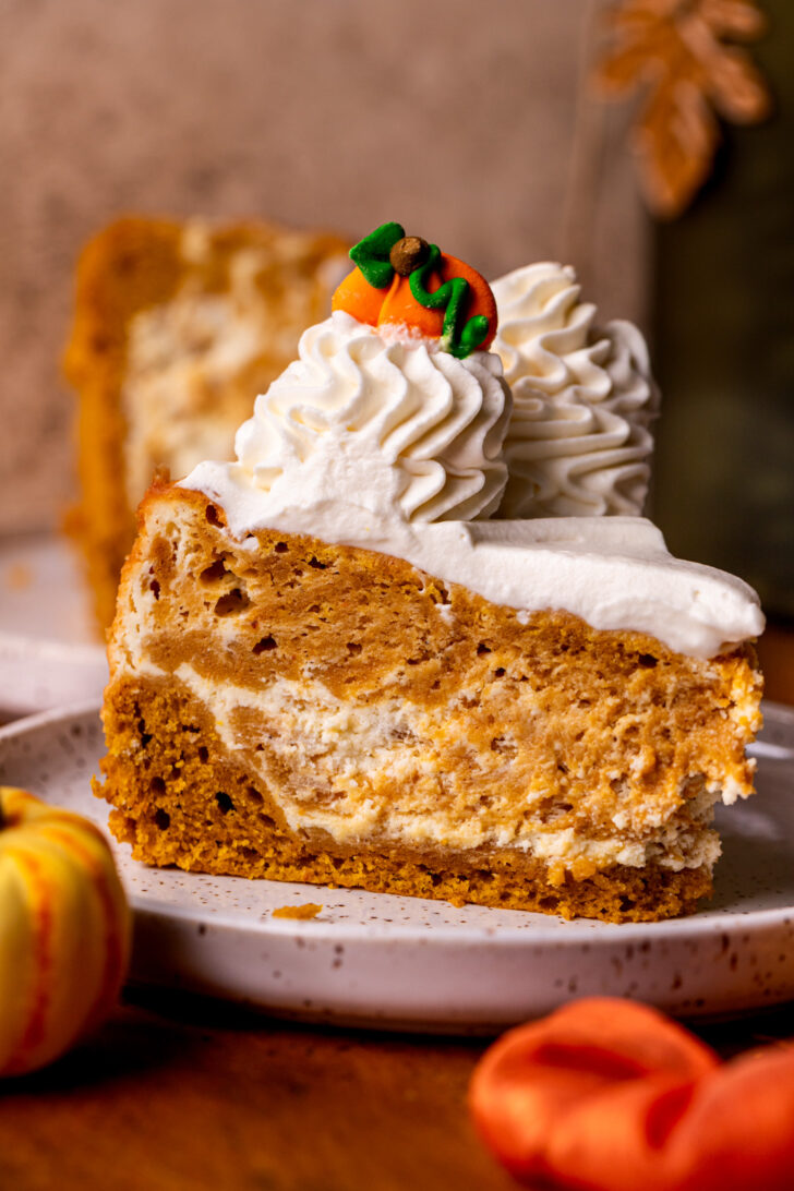 One slice of pumpkin cheesecake cake on a plate.