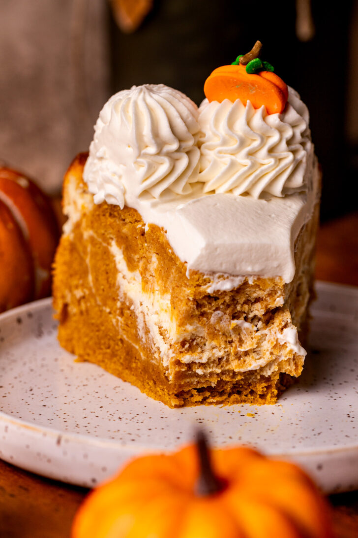 Pumpkin cheesecake cake on a plate with a bite missing.