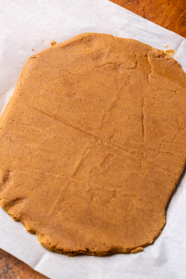 Cookie dough rolled out on parchment paper.