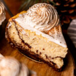 Slice of eggnog cheesecake on a wood platter.