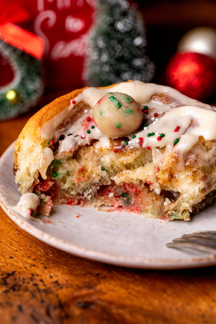 Side view of a sugar cookie cinnamon roll on a plate.