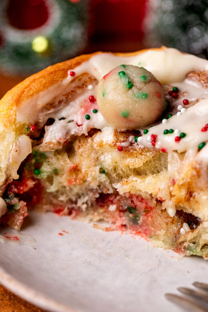 Bite missing from roll on a plate.