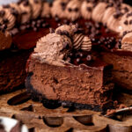 A slice of triple chocolate cheesecake on the wood platter.