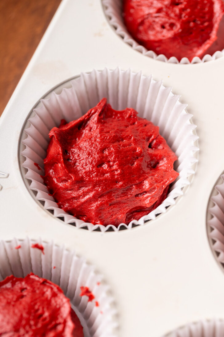 Red velvet cake batter in a cupcake pan.