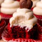 Bite missing from a red velvet cupcake.