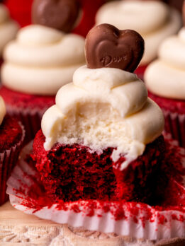 Bite missing from a red velvet cupcake.