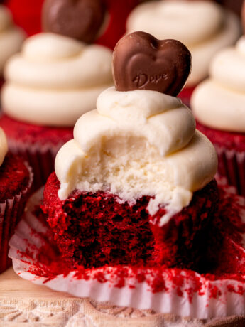 Bite missing from a red velvet cupcake.