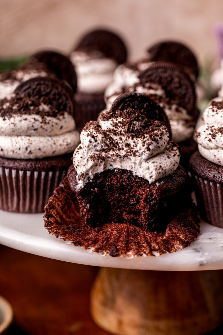 Bite missing Oreo cupcakes on a cake stand.