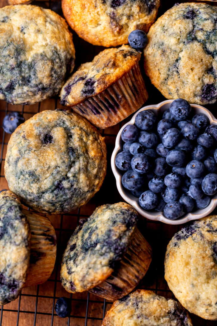 Baked bakery style blueberry muffins on a wire rack.