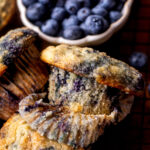 The wrapper is part way off on a bakery style blueberry muffin.