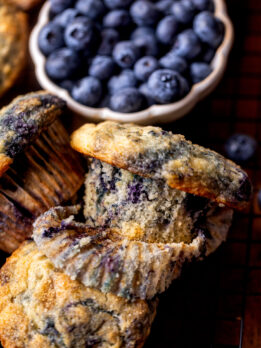 The wrapper is part way off on a bakery style blueberry muffin.