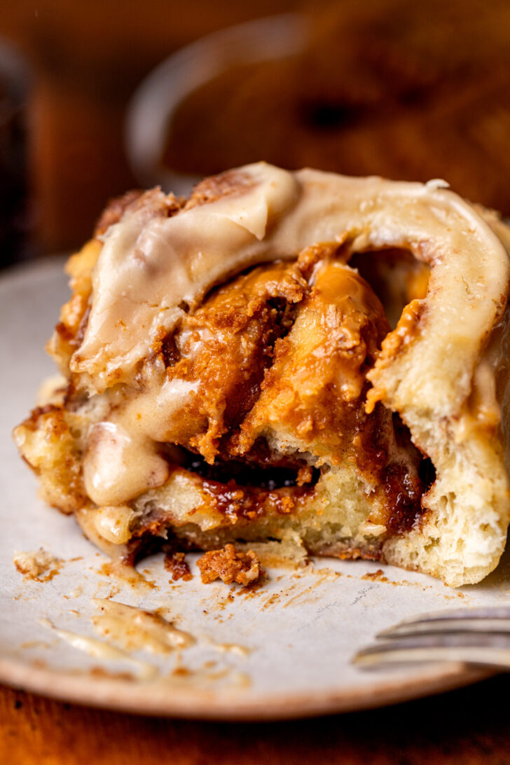 Bite missing from roll on a plate.