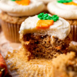 Bite missing from a carrot cake cupcake.