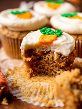 Bite missing from a carrot cake cupcake.
