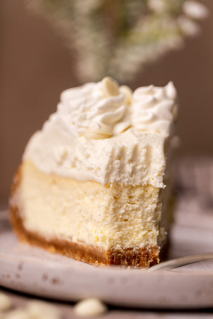 A bite missing from a slice of cheesecake on a plate.
