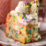 Slice of funfetti cake cheesecake with a bite missing.